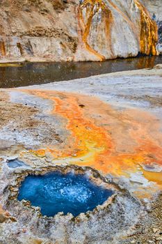 Vibrant blue Chinese with orange sediment runoff into river at Yellowstone