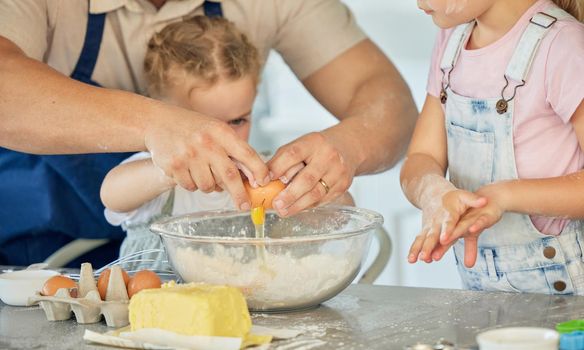 Father cracking egg into a bowl. Parent baking with his children. Family baking in the kitchen. Caucasian family baking together. Father bonding with his daughters and cooking. Kids baking together