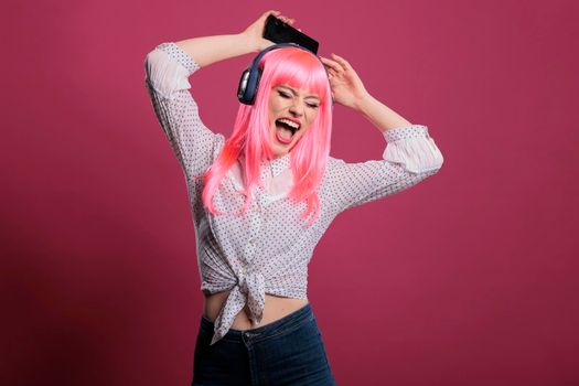 Positive person with pink hair having fun with mp3 music