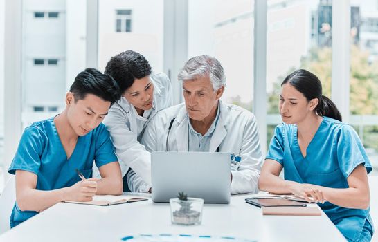 Developing healthcare and medicine as a cooperative science. a group of medical practitioners working together on a laptop in a medical office.