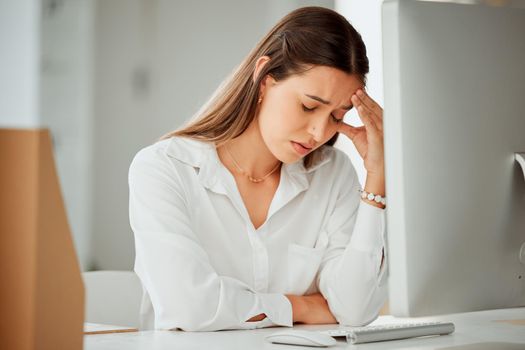 One anxious young hispanic business woman suffering with a headache while working on a computer in an office. Entrepreneur feeling overworked, tired and anxious about deadlines. Mentally frustrated with burnout and stress