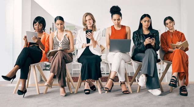 Women ruling the business world. a group of businesswomen sitting in a row in an office at work.