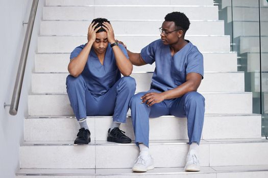 A supportive friend is a special friend. a young male doctor consoling a coworker at work.