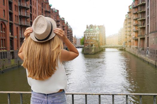Tourism in Germany. Beautiful young woman visiting Speicherstadt district in the port of Hamburg, Germany. UNESCO World Heritage Site. 