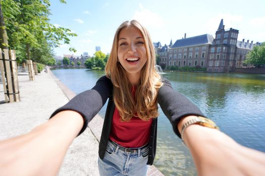 Selfie of young woman with the complex of buildings Binnenhof on Hofvijver in The Hague, Netherlands