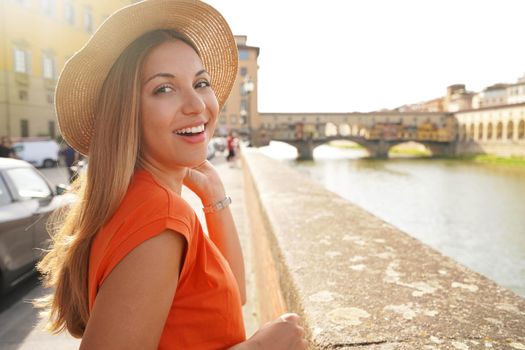 Close-up portrait of attractive young tourist woman who turns around and looking at camera on sunset in Florence, Italy