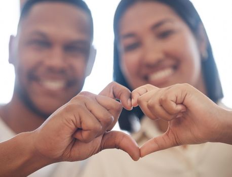 Closeup of mixed race couple making heart shape with hands. Two lovers showing heart sign by joining fingers. Shape of love