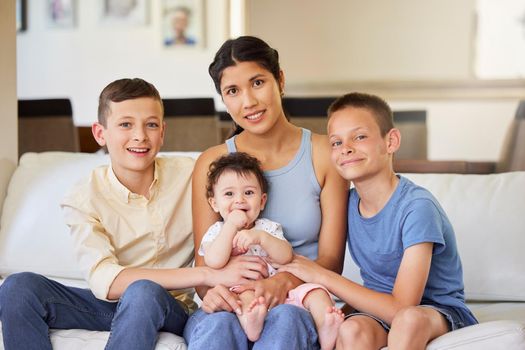 Portrait of a multiracial family at home. Mother with her adoptive sons. Young mother relaxing with her children. Mixed race family relaxing together at home. Boys spending time with their parent