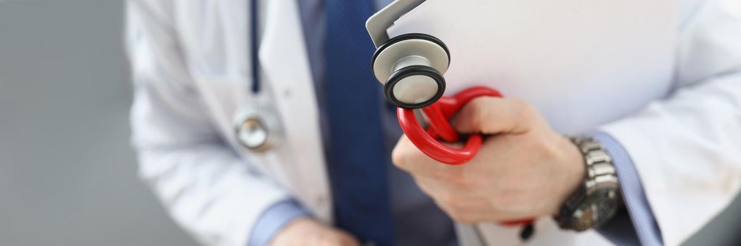 Doctor holding medical equipment red stethoscope and patient medical history