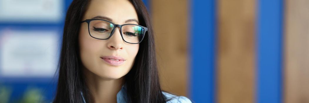 Attractive young businesswoman looking down on computer screen, wearing glasses