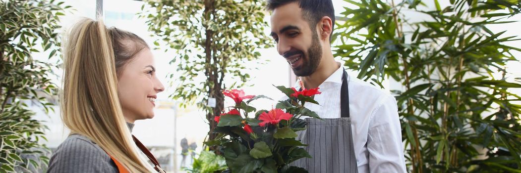 Man consultant gives flowers in pot to his colleague, show liking for her