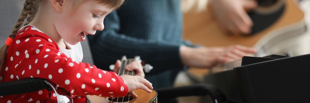 Happy child playing guitar, learn new song on musical instrument