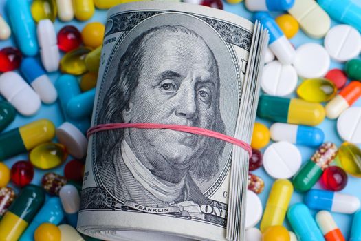 Pack of dollars lay on medicine pills, capsules with hard glance to the camera