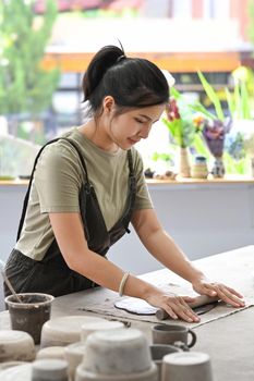 Shot of young asian woman wearing apron creating handmade ceramic bowl in a pottery workshop