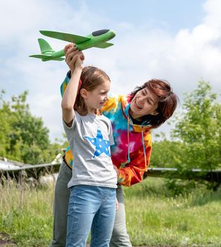 Mother and daughter playing with toy plane