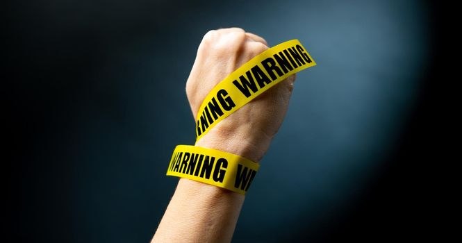 Hand with warning tape shows signs
