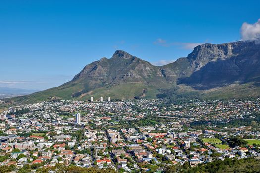 The landscape of an urban town surrounded by green plants and mountains on a summer day. Scenic view of a holiday destination near nature. Aerial view of the beautiful city of Cape Town, South Africa