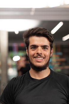 Portrait of a smiling personal trainer, with beard, at local sport and fitness center, during a training session