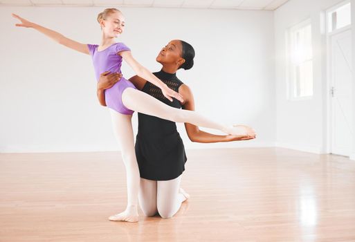 To teach is to pass out peaces of yourself. a little girl practicing ballet with her teacher in a dance studio.