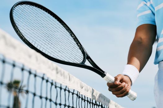 Give it your best shot. an unrecognizable man holding a racket during a tennis match.