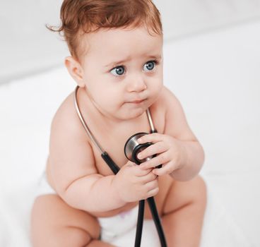 Erm, lady doctor will this hurt. an adorable little baby boy hold a stethoscope in a clinic during his checkup.