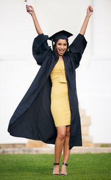 Its a bright and beautiful day. Portrait of a young woman cheering on graduation day.