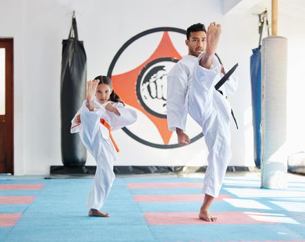 Dont let her size fool you. a young man and cute little girl practicing karate in a studio.