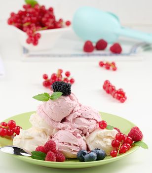 Vanilla and raspberry ice cream scoops on a round green plate