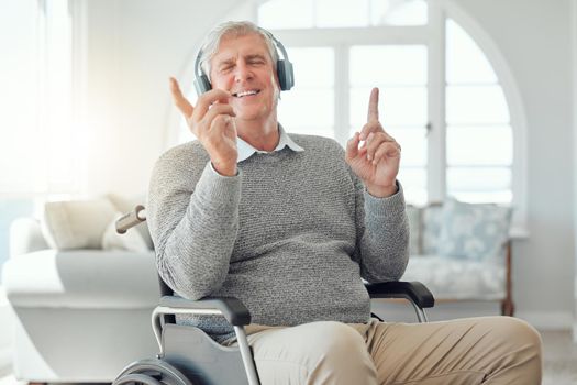 My soul is free. an elderly man enjoying some music while sitting in the lounge at home.