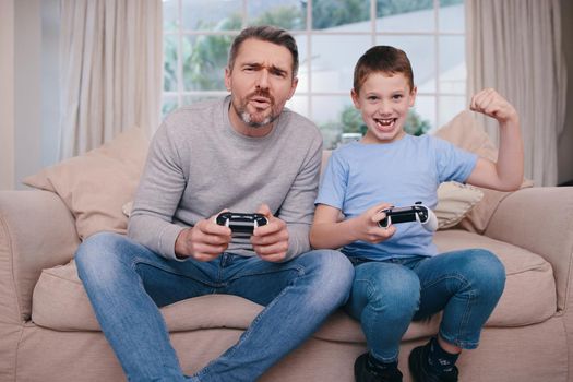 Competition inspired. a father and son playing video games while bonding on the couch at home.