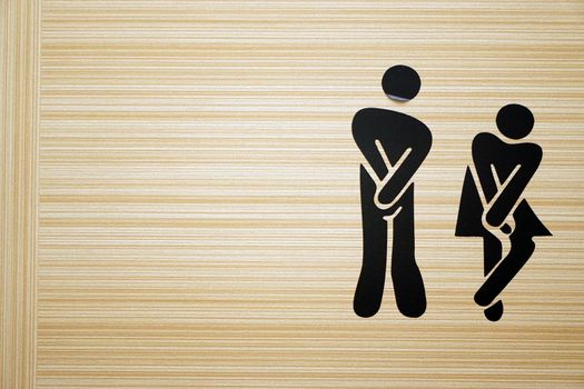 Comic toilet sign symbols with woman and men on wooden background