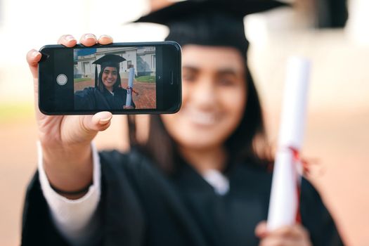 Ill remember this moment forever. a female graduate taking selfies using her smartphone.