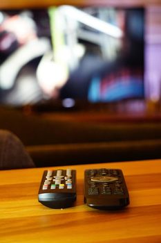 Two television remote controllers on wooden background image with shallow depth of field