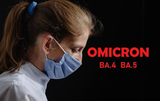 A female doctor or nurse is tired and upset at work. The health worker is saddened. Omicron inscription on black background. Photo of a woman wearing a medical protective mask on a black background. Pandemic covid 19 concept, Omicron Ba.4 and Ba.5