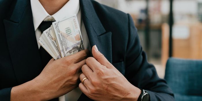 Closeup conceptual photo of bribed man putting money in the suit pocket. banner concept.