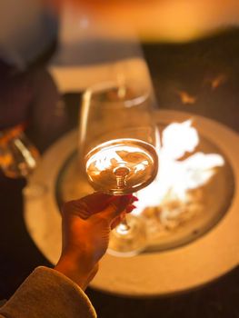 Woman holding wine glass by the fire pit at night