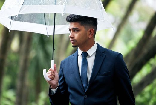 Theres new opportunity around every corner. a young businessman holding an umbrella on a rainy day in the city.