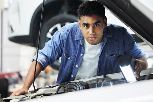 Just a simple manly man. Portrait of a handsome young male mechanic working on the engine of a car during a service.