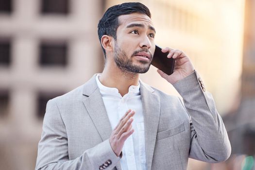 Can I go ahead with the deal. a handsome young businessman standing in the city and using his cellphone.