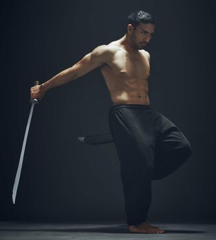 I practice to be the best. Full length shot of a handsome young man standing alone in the studio and posing with a broadsword.