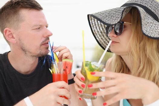 A couple on vacation drinking tropical cocktails, close-up