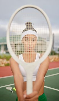 Get your grip right and the rest will follow. a sporty young woman holding a tennis racket in front of her face.
