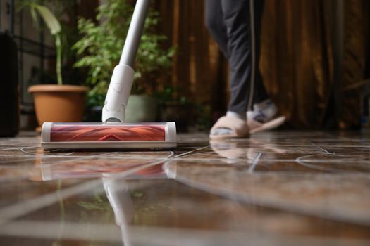 Cordless vacuum cleaner with turbo brush cleans tiles in living room