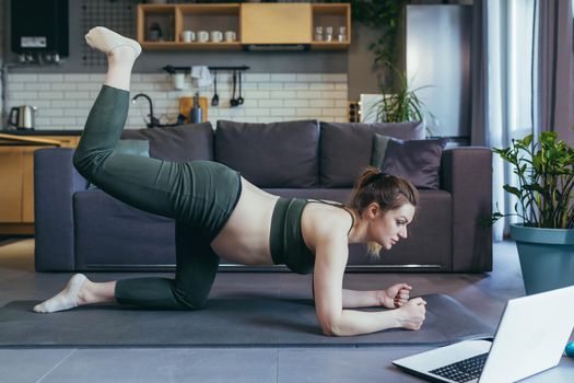 Pregnant woman at home doing fitness uses laptop for online classes