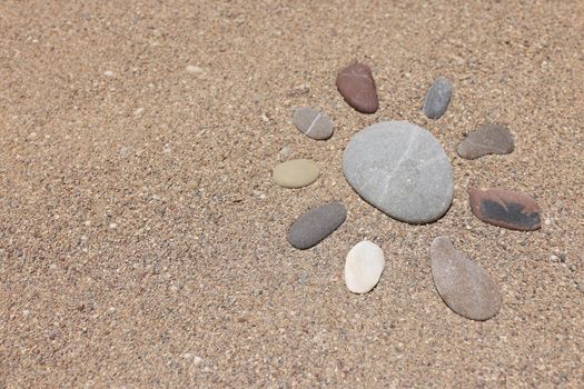 Stones put in form of sun, sandstone on sandy beach, hot sand, holiday time