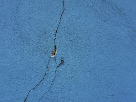 A large crack in the old blue plaster wall.