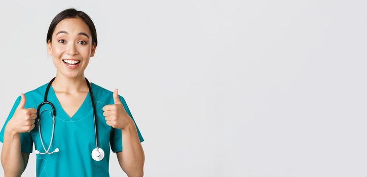 Healthcare workers, preventing virus, quarantine campaign concept. Young supportive asian nurse give thumbs-up. Doctor cheer-up patient, encourage someone or compliment, white background