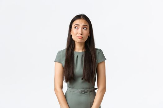 Small business owners, women entrepreneurs concept. Indecisive timid asian female worried about starting own startup, looking confused and doubtful, gazing upper left corner hesitant