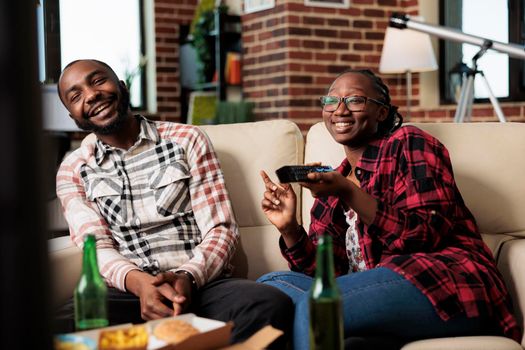Cheerful couple laughing and watching television together