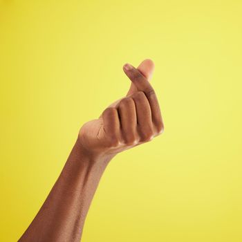 Ka ching. Studio shot of an unrecognisable man rubbing his fingers together against a yellow background.